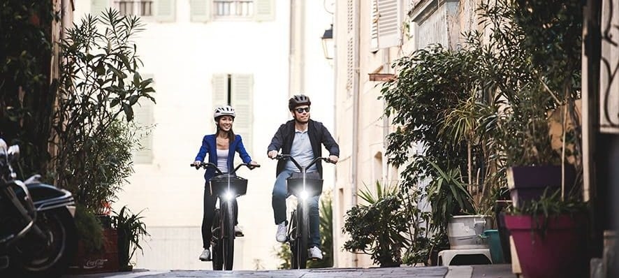 Eine Frau und ein Mann fahren auf einem Specialzed e-Bike, umgeben von Pflanzen