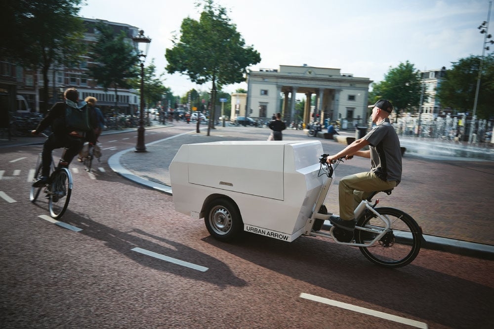 Ein Urban Arrow Tender 4 Lastenrad fährt auf einer städtischen Straße.