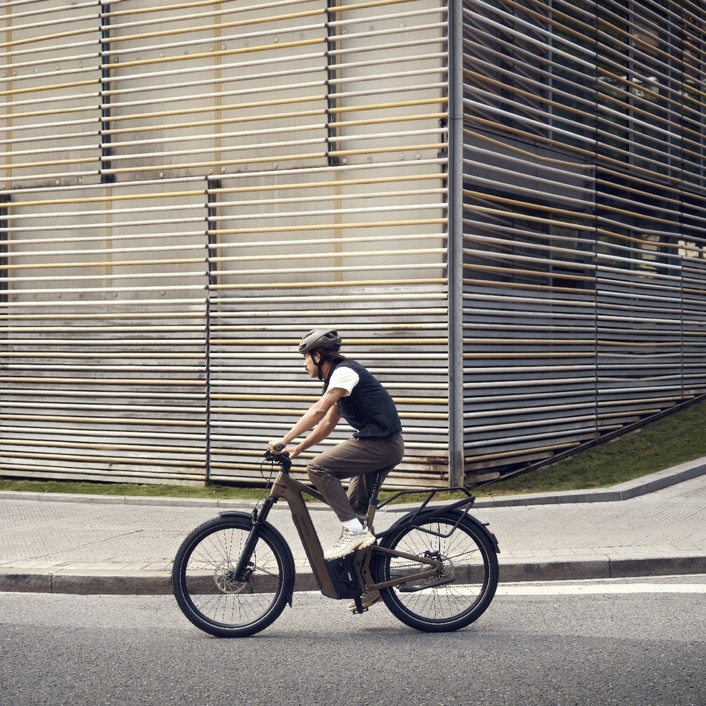 Eine Person auf einem Riese & Müller Delite e-Bike fährt an einer besonderen Wand entlang