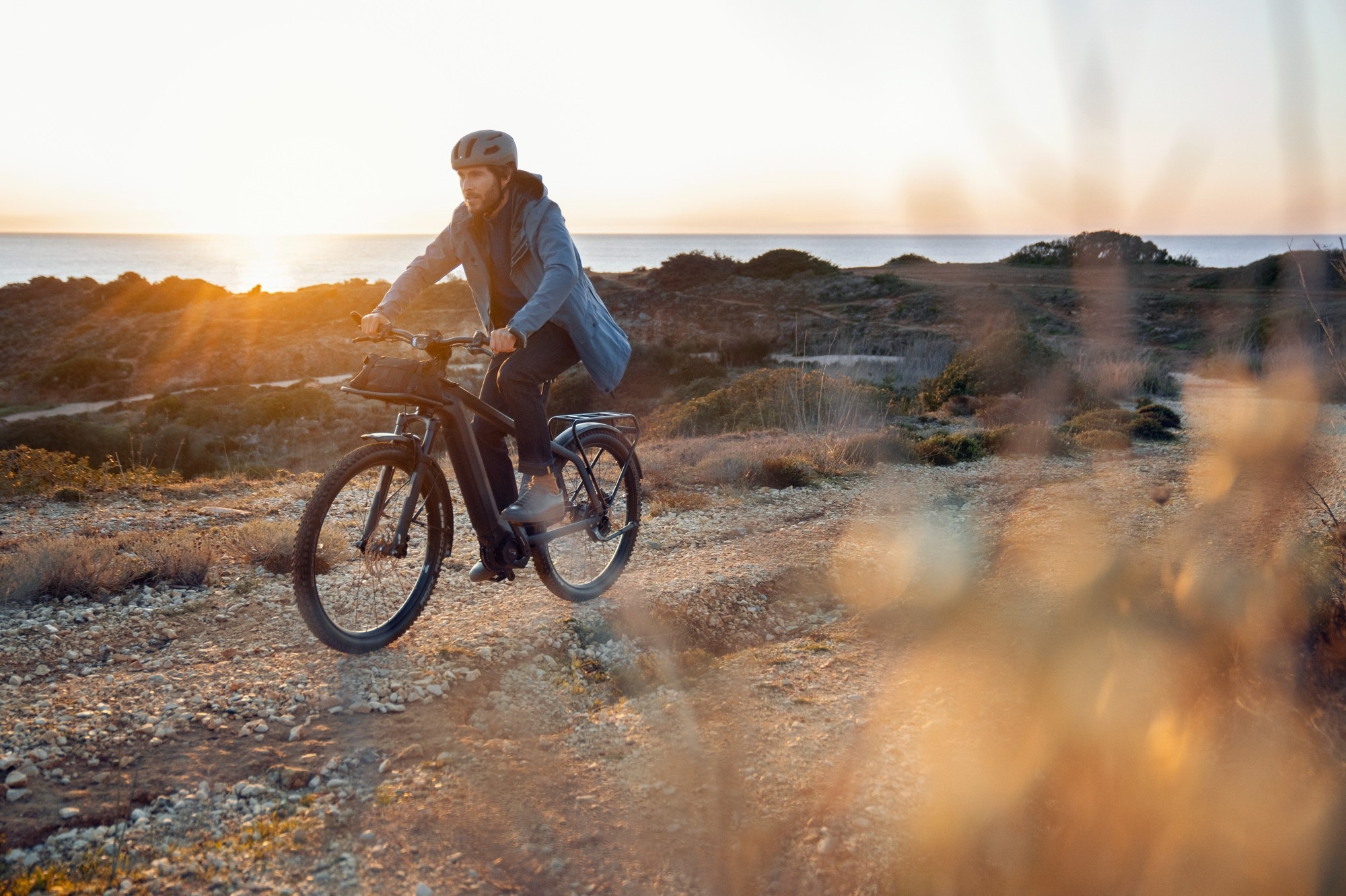 Das Bild zeigt ein Riese & Müller MY2020 Charger3 E-Bike, das in einer malerischen Landschaft gefahren wird.