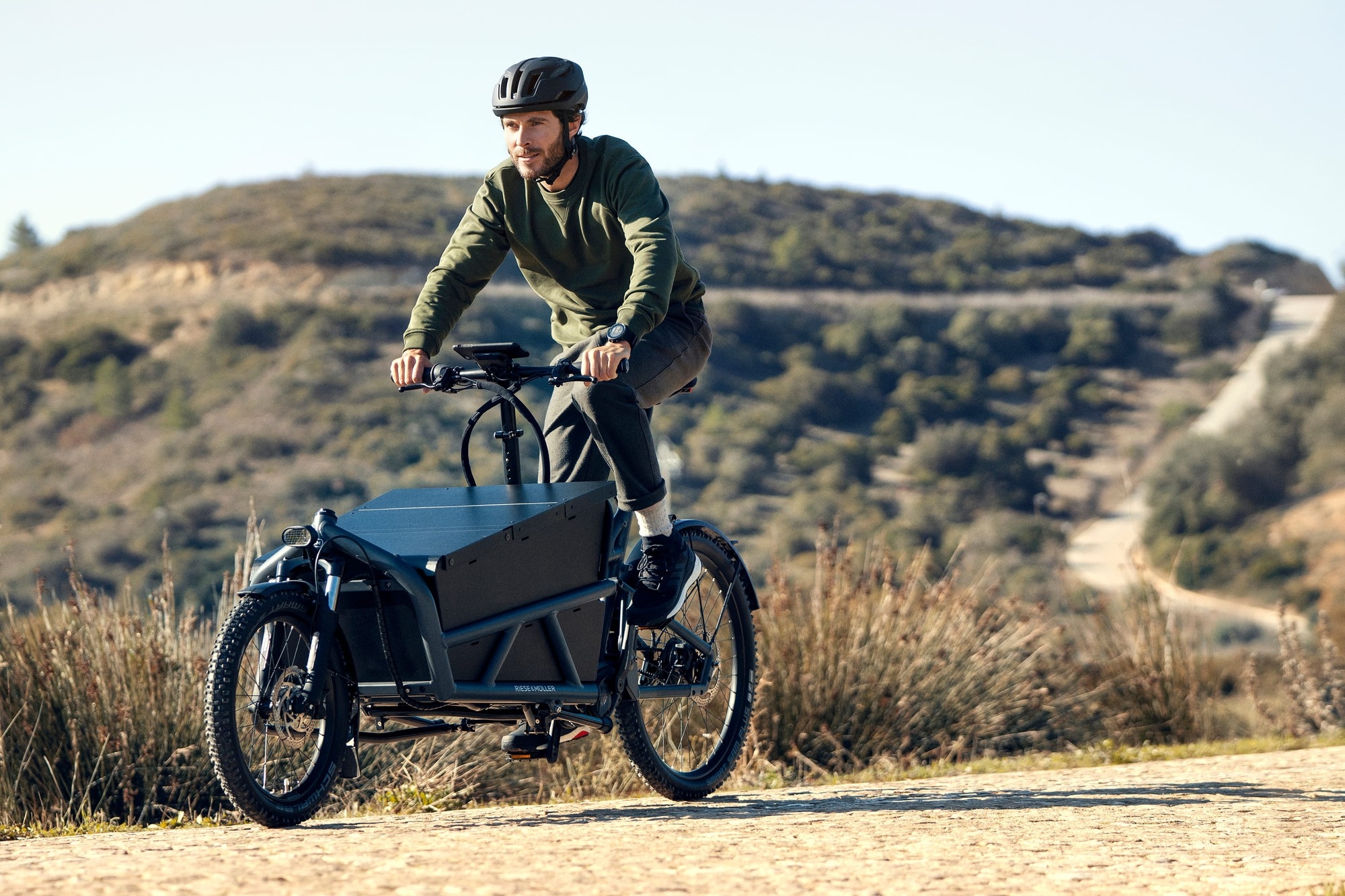 Das Bild zeigt ein Riese & Müller Load60 E-Bike, das in einer natürlichen Umgebung gefahren wird.