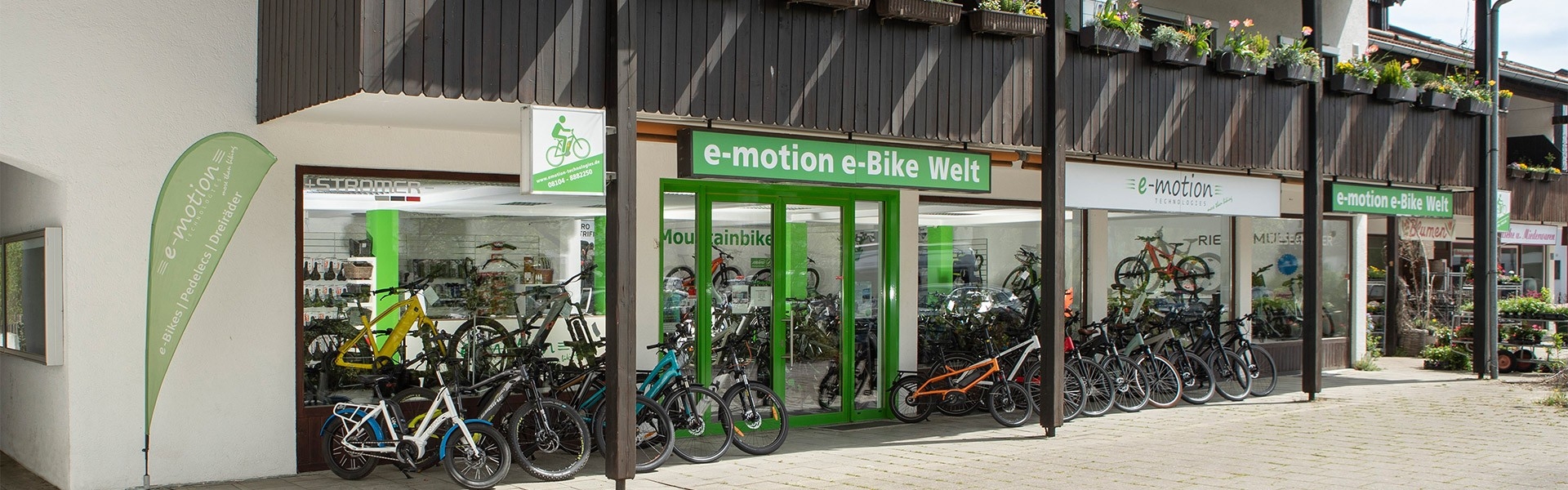 Das Bild zeigt die Fassade eines E-Bike Shops in München Süd, betitelt als "e-motion e-Bike Welt".