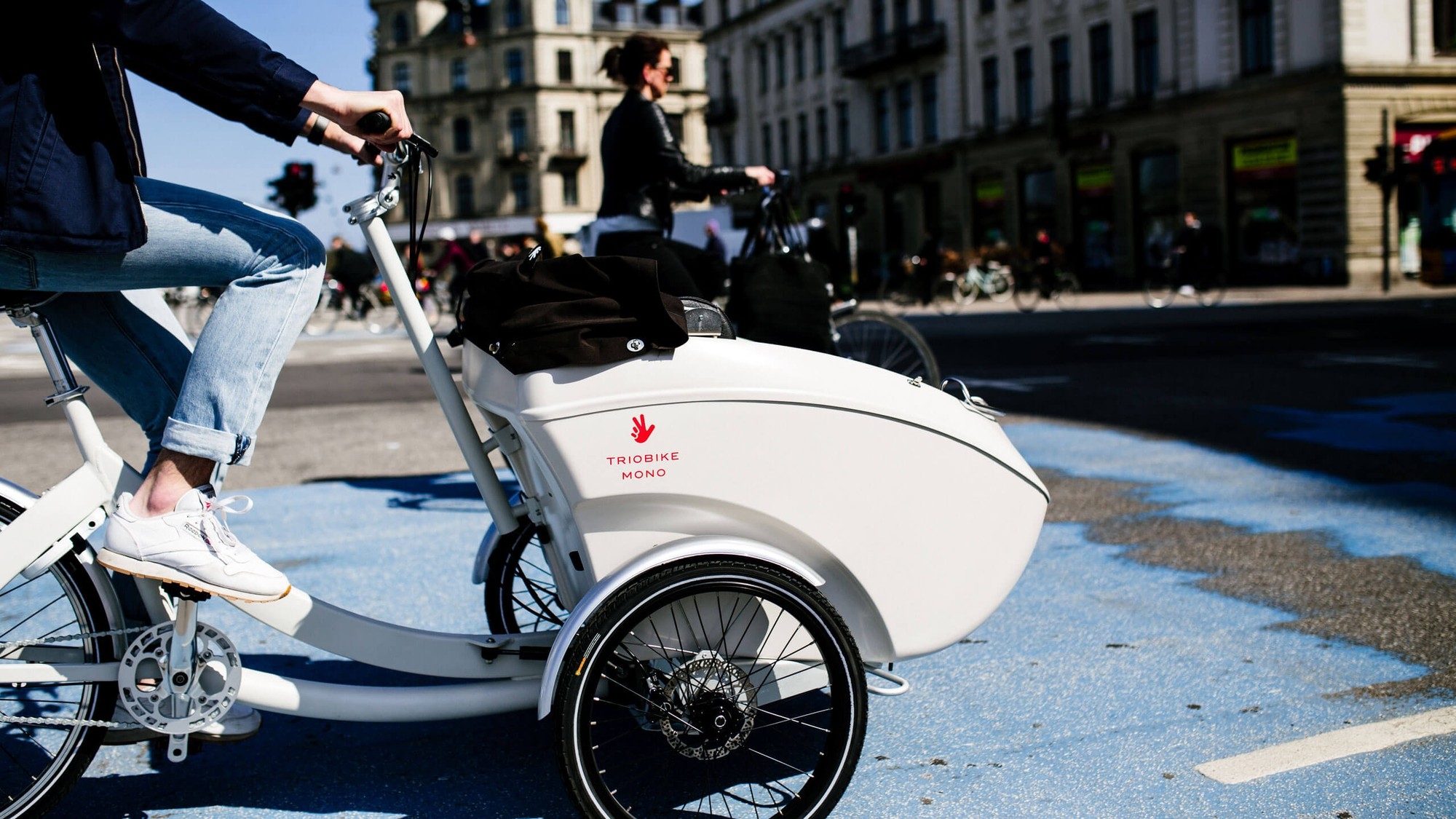 Eine Person fährt auf dem Triobike Mono Lastenrad über die Straße